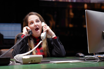 A female hotel manager is under stress in front of a computer that answers the hotel's customer calls. A lot of phone calls. Funny facial expression, emotions, feelings, problems reaction, stress.