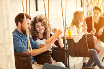 Male and female read book on swing