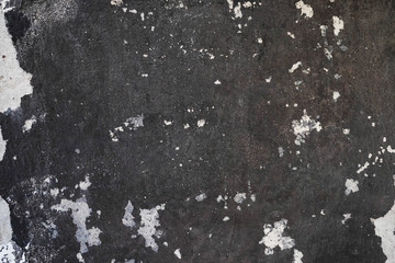 Black-and-white stone wall as a background. Textured stone black wall.  Peeling paint on the concrete surface.  