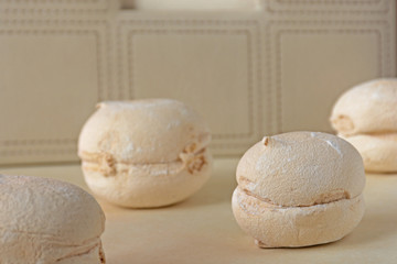 Beige sweet meringue on colored background. Pastel french cookies macarons on light background. Gift for holidays. Soft focus. Copy space