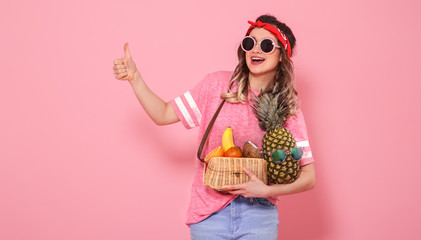 Portrait of a girl with healthy food, fruits, on a pink background