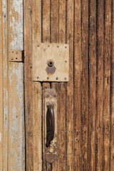 Wooden vintage door with keyhole and rusty iron handle.