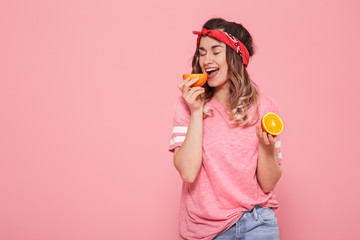 Portrait of a girl with oranges in hand, on a pink background