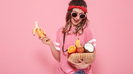 Portrait of a girl with healthy food, fruits, on a pink background