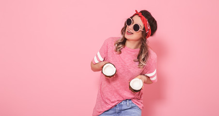 Portrait of a girl with coconuts, on a pink background