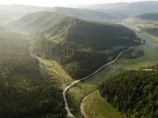 Road through mountains and forest captured from above