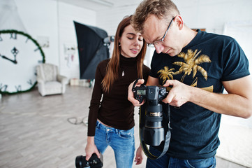 The team of two photographers looking at camera final work material on studio.