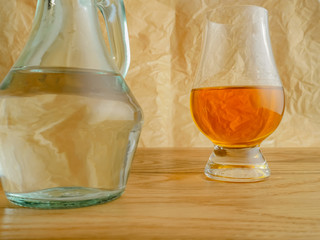 Irish Whiskey Glass and Water Jug on Wood and Paper Background Close Up