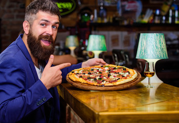 Hipster hungry eat italian pizza. Pizza favorite restaurant food. Fresh hot pizza for dinner. Hipster client sit at bar counter. Man received delicious pizza. Enjoy your meal. Cheat meal concept