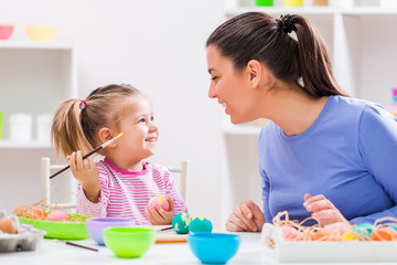 Happy mother and daughter coloring eggs for Easter. 