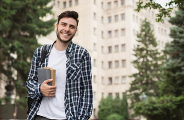 Happy male student holding books outdoors
