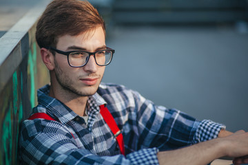 Young man sitting at skate park at sunset