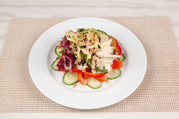 Vegetable salad with corn and mushrooms on a white plate on the table.