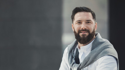 Friendly stylish businessman standing outdoors, copy space