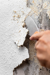 Alte Rauhfasertapete wird mit einem Spachtel oder Malerspatel von der Wand entfernt oder abgekratzt