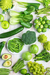 Healthy eating vegan concept. Green vegetables fruits on white table broccoli sprouts peas avocado courgette beans bok choy celery apple grapes, top view, selective focus