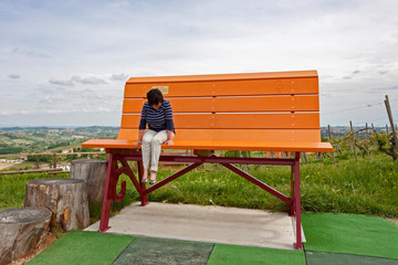 woman sitting on one of the colorful Big Bench, placed betweenhe vineyards and the countryside of...