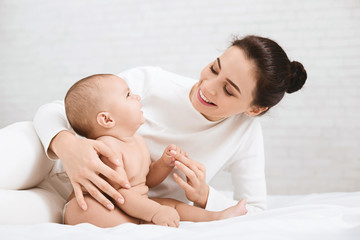 Mother playing with her baby in bedroom.