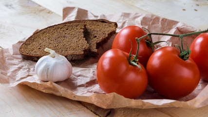 branch with tomatoes, garlic and bread on a wooden background