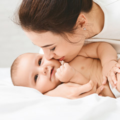 Mother kissing her sweet adorable baby in bed