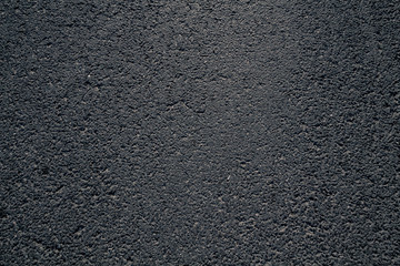 Dark asphalt texture on a sunny and hot summer day.