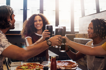 Multi-ethnic group of friends toasting cold drinks at restaurant