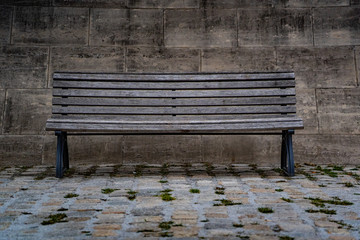 old wooden bench in the city heart of berlin germany, isolated bench in front of a stone wall 