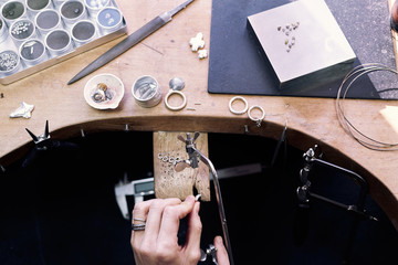 Jeweler at work in jewelery workshop, woman hands making silver thing. tools set.