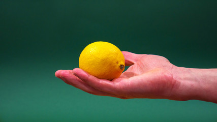Lemon in hand on green background isolation