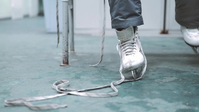 Unrecognizable girl puts on ice skates. Close-up of legs with skates in the dressing room.