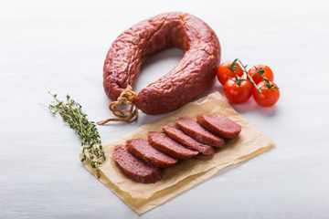 Food, meat and delicious concept - sliced horse meat sausage with tomato and cumin