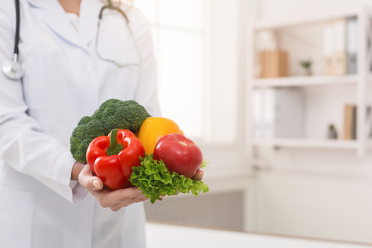 Nutritionist holding fresh vegetables in her office