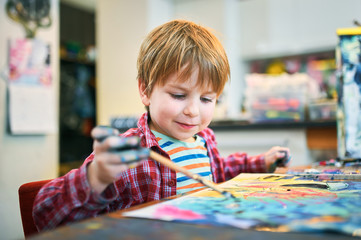 Cute happy little boy, adorable preschooler, painting in a sunny art studio. Young artist at work