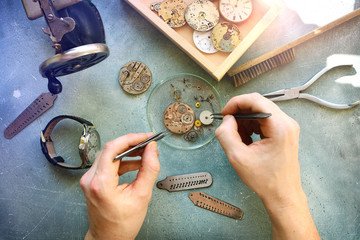 Watchmaker at work in workshop. Flat lay. Workplace of watch repairer. Process of repair mechanical...