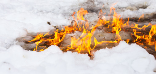 Flame of fire on white snow in winter