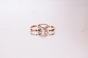 3 wedding gold rings on the white background glass with water drops . Wedding. Diamonds.