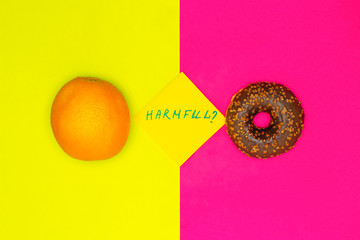 Healthy food vs harmful snacks. Choice concept. Orange and donut. Trend Colors Flat Lay.