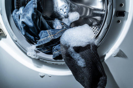 Drum Of A Modern Washing Machine Close-up With Clothes In The Foam.