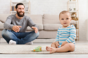 Father playing with his baby son on floor at home