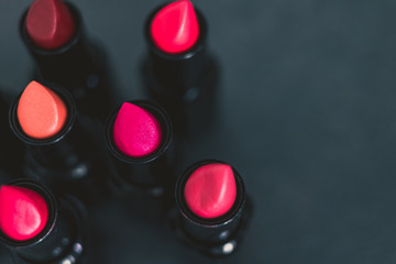 group of red pink and nude lipsticks with different colors and textures on dark table