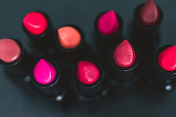 group of red pink and nude lipsticks with different colors and textures on dark table