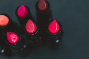 group of red pink and nude lipsticks with different colors and textures on dark table