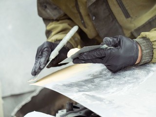 cute guy with glasses putty a car hood section of a garage in black gloves