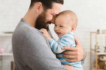 Fototapeten Loving father embracing his cute baby son © Prostock-studio