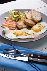 Breakfast if two fried eggs with salmon, hash browns