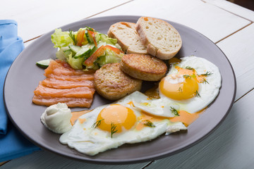 Breakfast if two fried eggs with salmon, hash browns