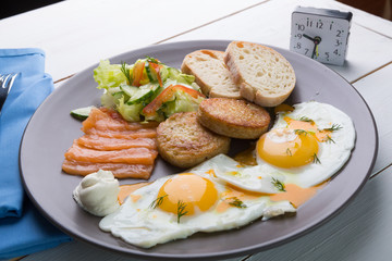 Breakfast if two fried eggs with salmon, hash browns