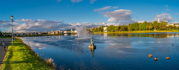 Panoramic view of Reykjavik downtown with lake on Iceland during sunset with rainbow, summer time - obrazy, fototapety, plakaty