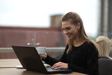Fototapeta na wymiar Young beautiful woman using laptop and drinking coffee
