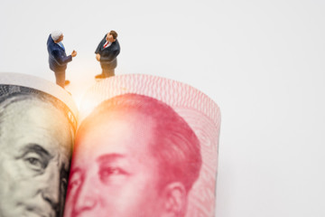 Miniature business men with US dollar and China Yuan banknote on cooperate meeting for trade war.Copy space and business concept. -Image.